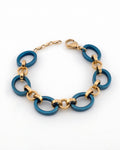 Studio product photo of a blue and gold bracelet curved in a circle on a white background