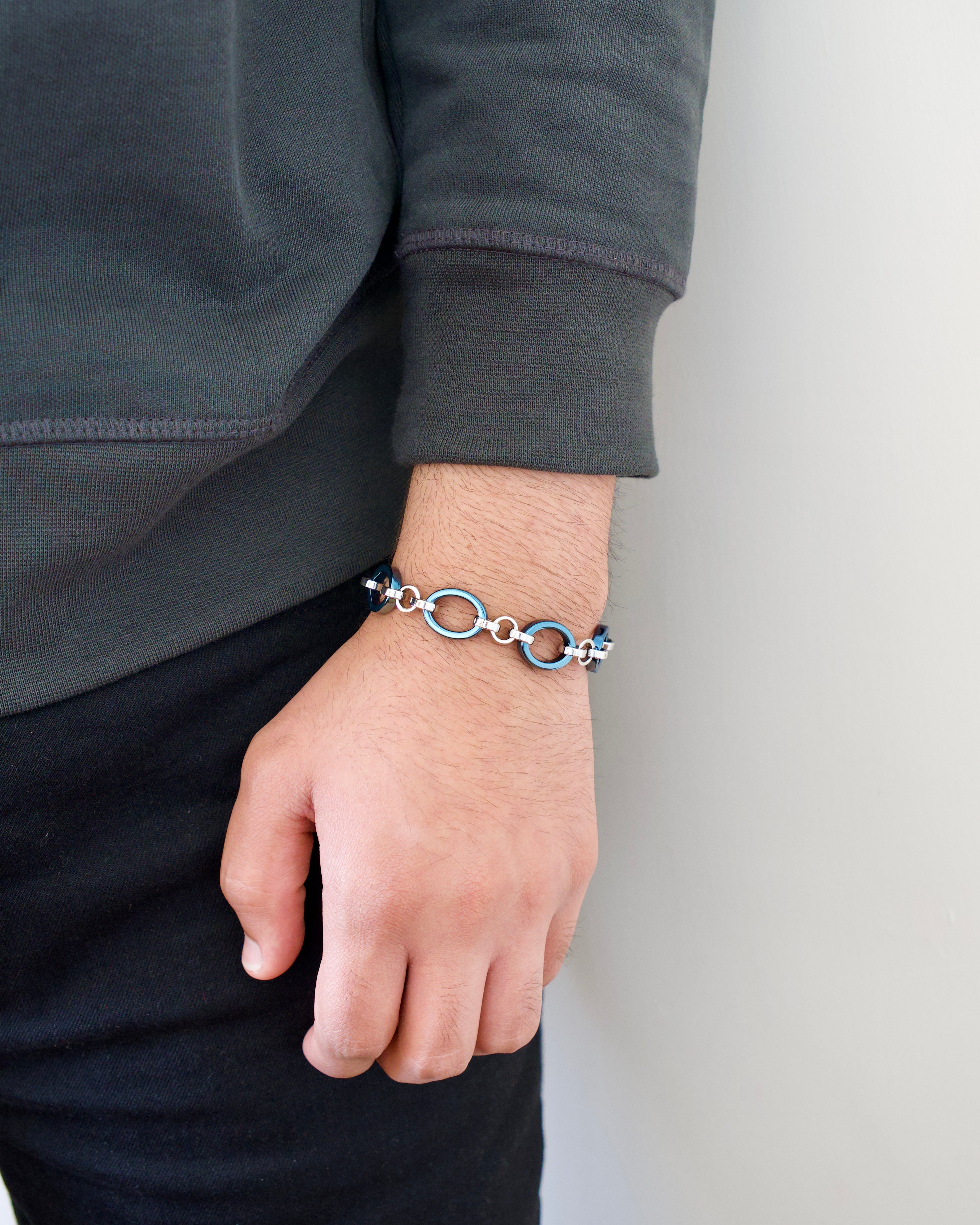 Man wearing a light blue and silver chain bracelet on a plain white background