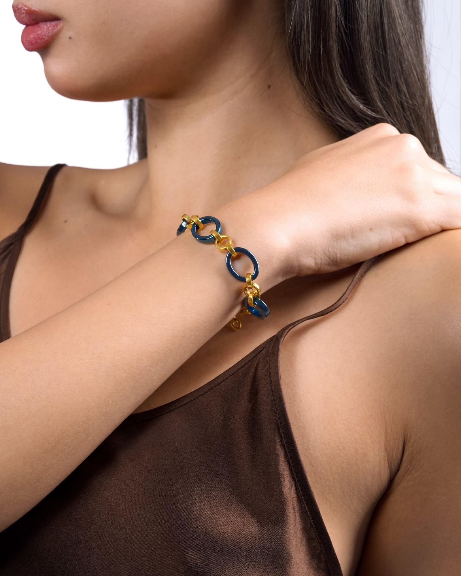 Women's wrist wearing Meridian Chain Bracelet in Midnight Gold, deep blue titanium & 18K yellow gold PVD, studio shot - hand resting on shoulder