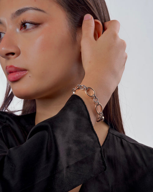 Women's wrist wearing Meridian Chain Bracelet in Frosty Rose, 18K rose & white gold PVD stainless steel, studio shot - wrist raised, holding hair