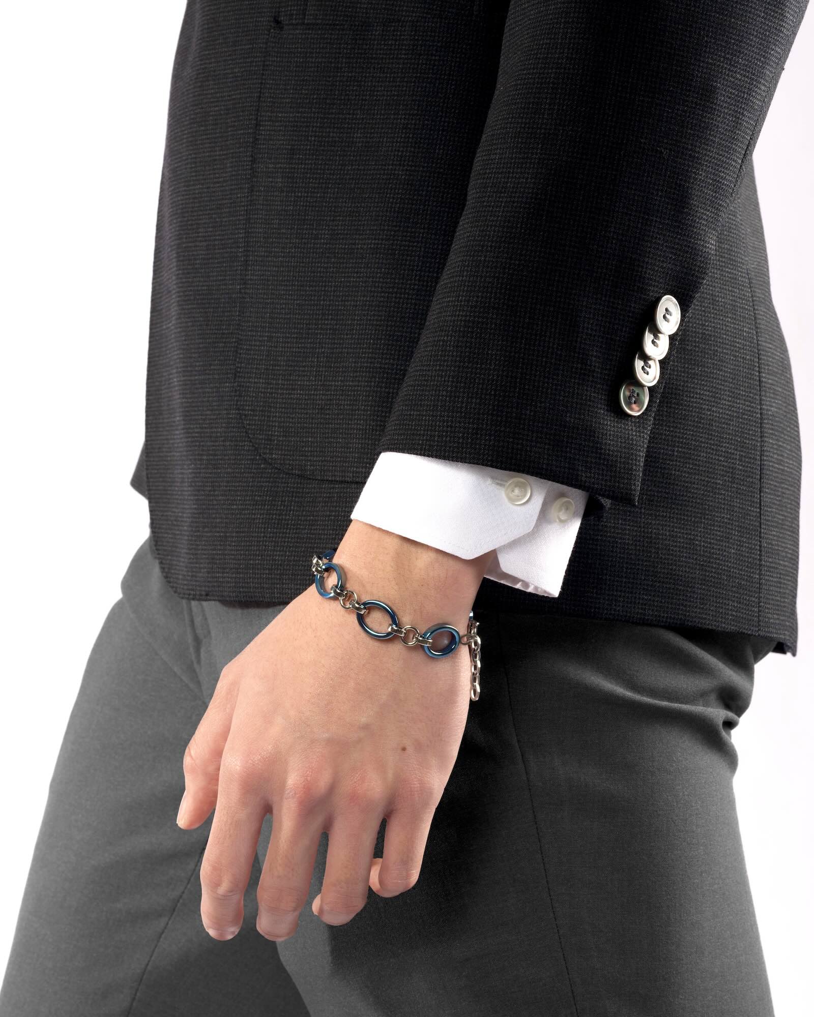 Men's wrist wearing Meridian Chain Bracelet in Glacier Blue, ice blue titanium & 18K white gold PVD, studio shot - arm at side, relaxed natural stance