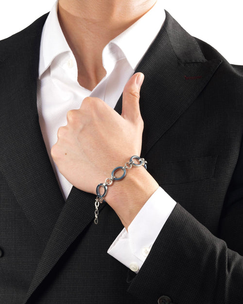 Men's wrist wearing Meridian Chain Bracelet in Glacier Blue, ice blue titanium & 18K white gold PVD, studio shot - hand raised holding suit jacket lapel