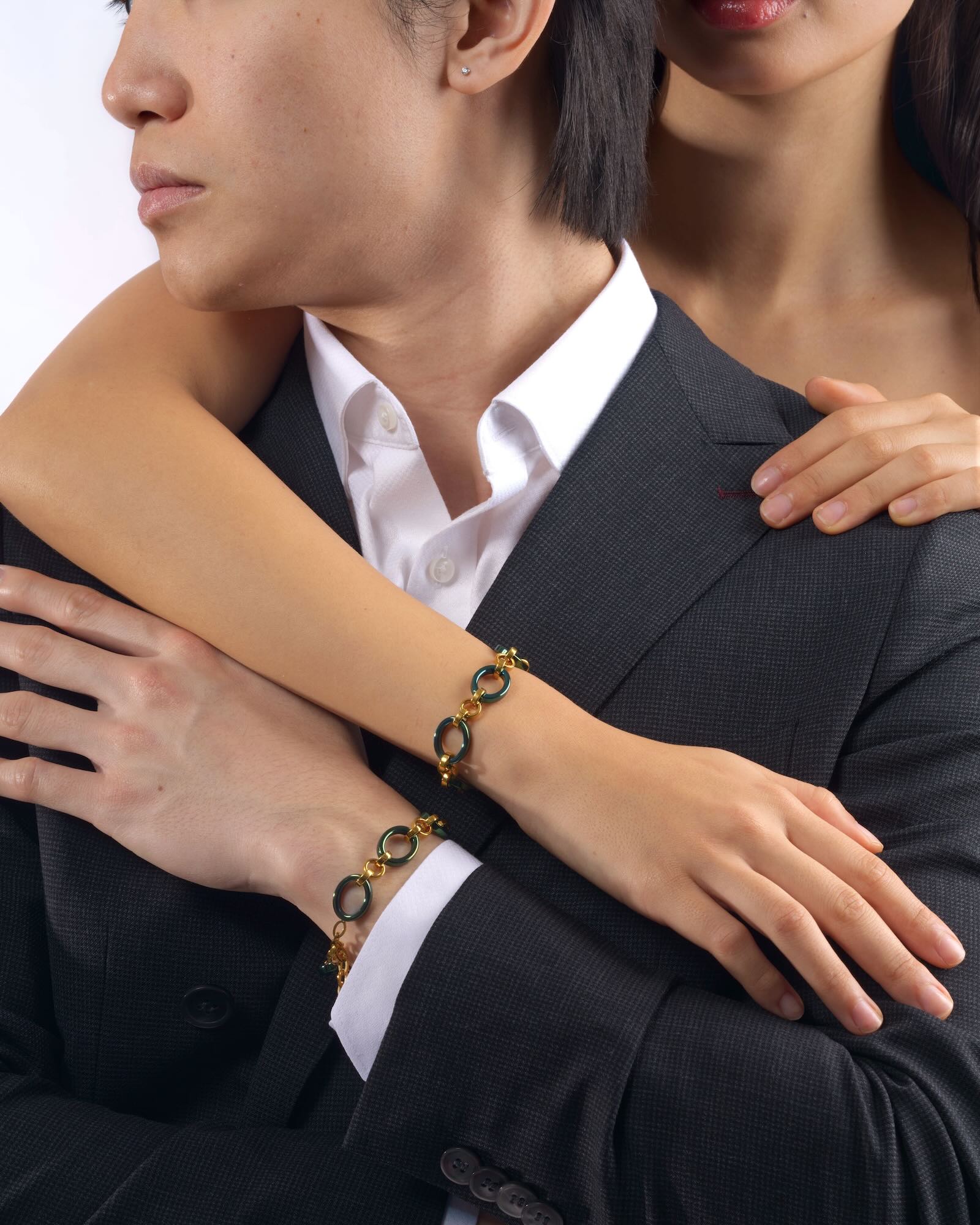 Male and female models wearing Reversible Meridian Chain Bracelet Green Lagoon, wrists side by side on shoulder, studio