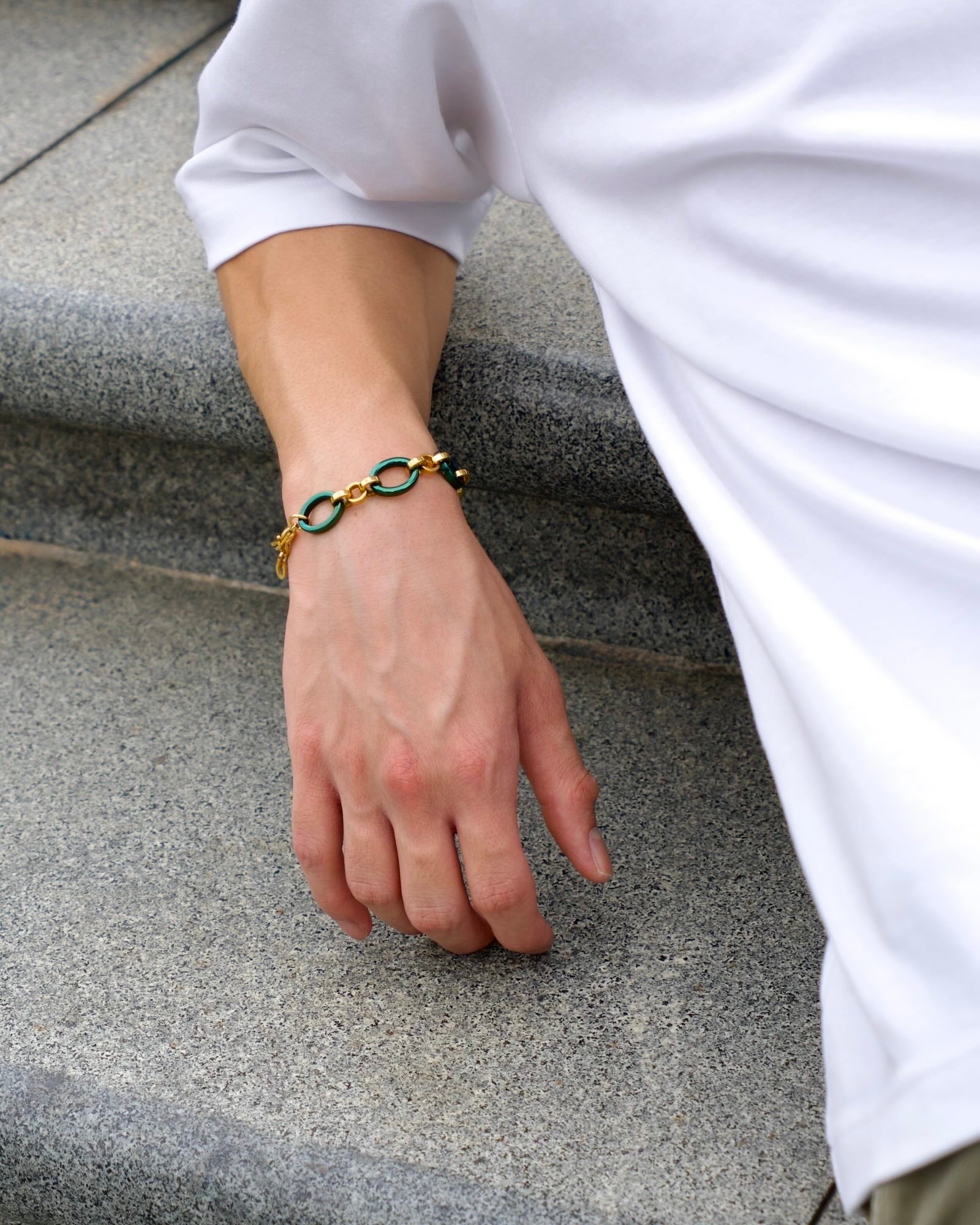 Men's wrist wearing Reversible Meridian Chain Bracelet Green Lagoon, wrist resting along stone staircase, lying down
